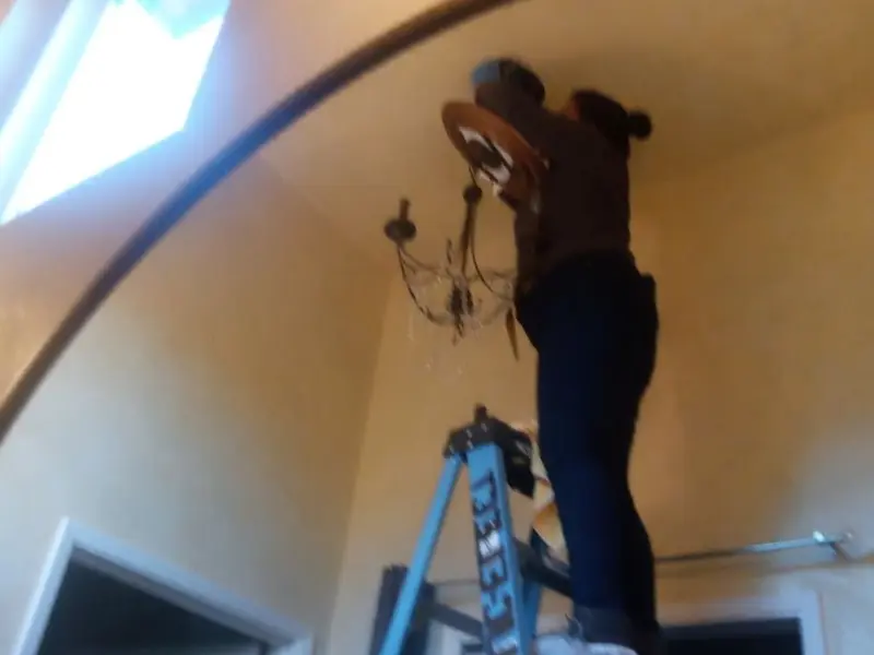 Electrician installing a chandelier in a Alvin residence